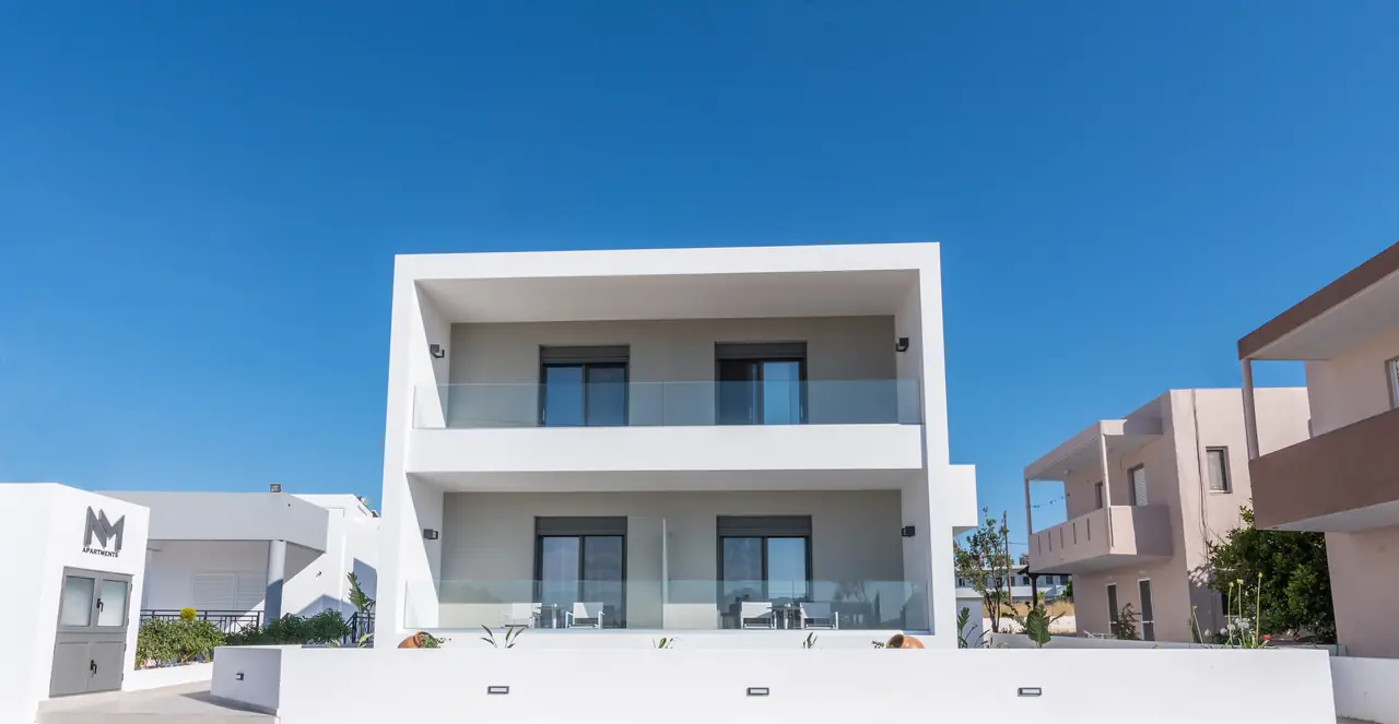 The white two-storey NM Apartments building under a clear blue sky