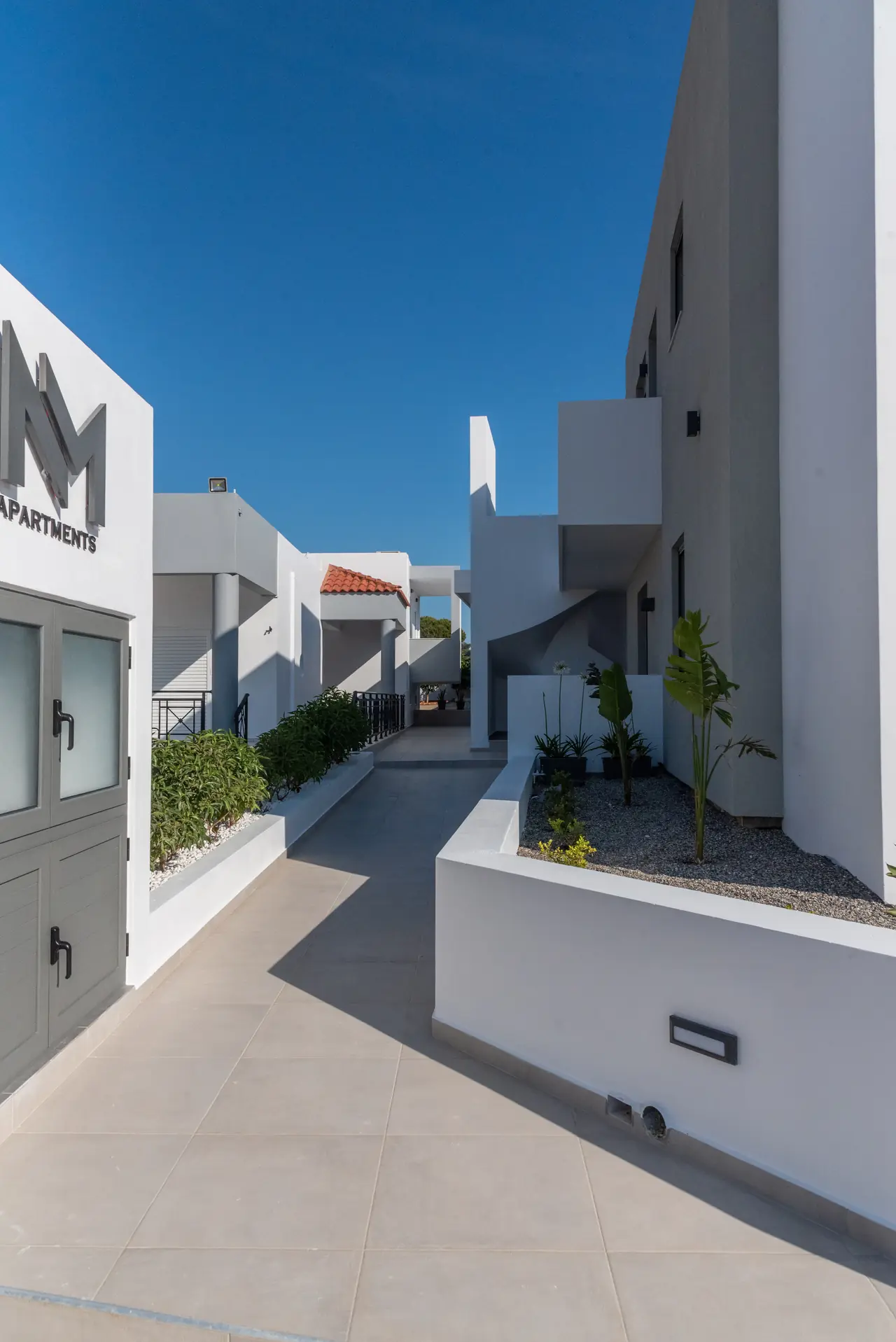 Walkway between the apartments with the NM sign and planters
