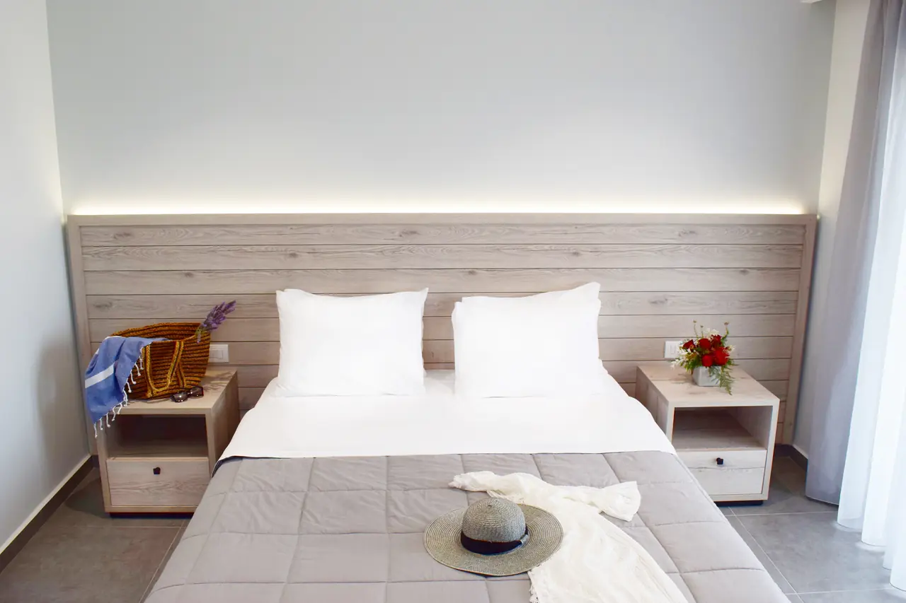 Made bed with a straw hat, summer dress and beach bag
