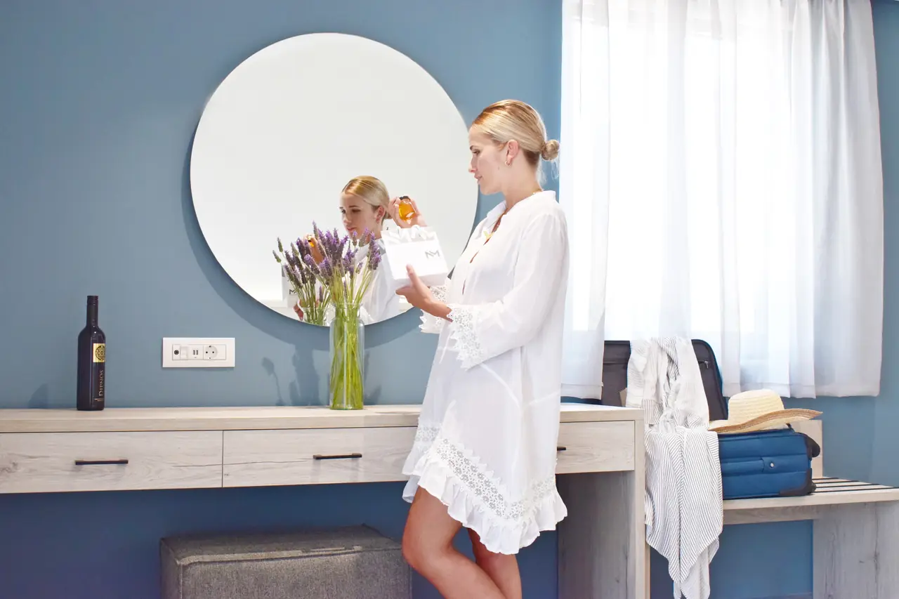 Guest in a white dress getting ready at the bedroom mirror