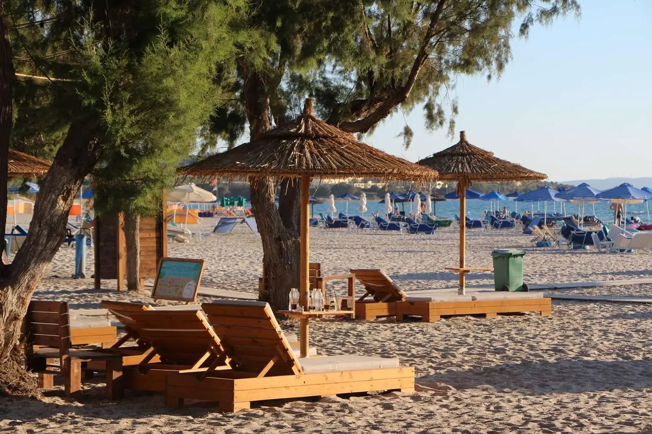 Straw umbrellas and sunbeds under tamarisk trees on Mastichari beach